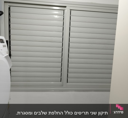 תריסים אפורים סגורים על חלון קיר לבן